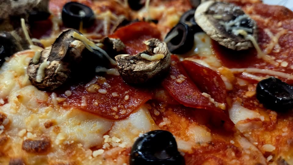 A pepperoni, mushroom and black olive pizza from Dough Riot, shot close on the surface.